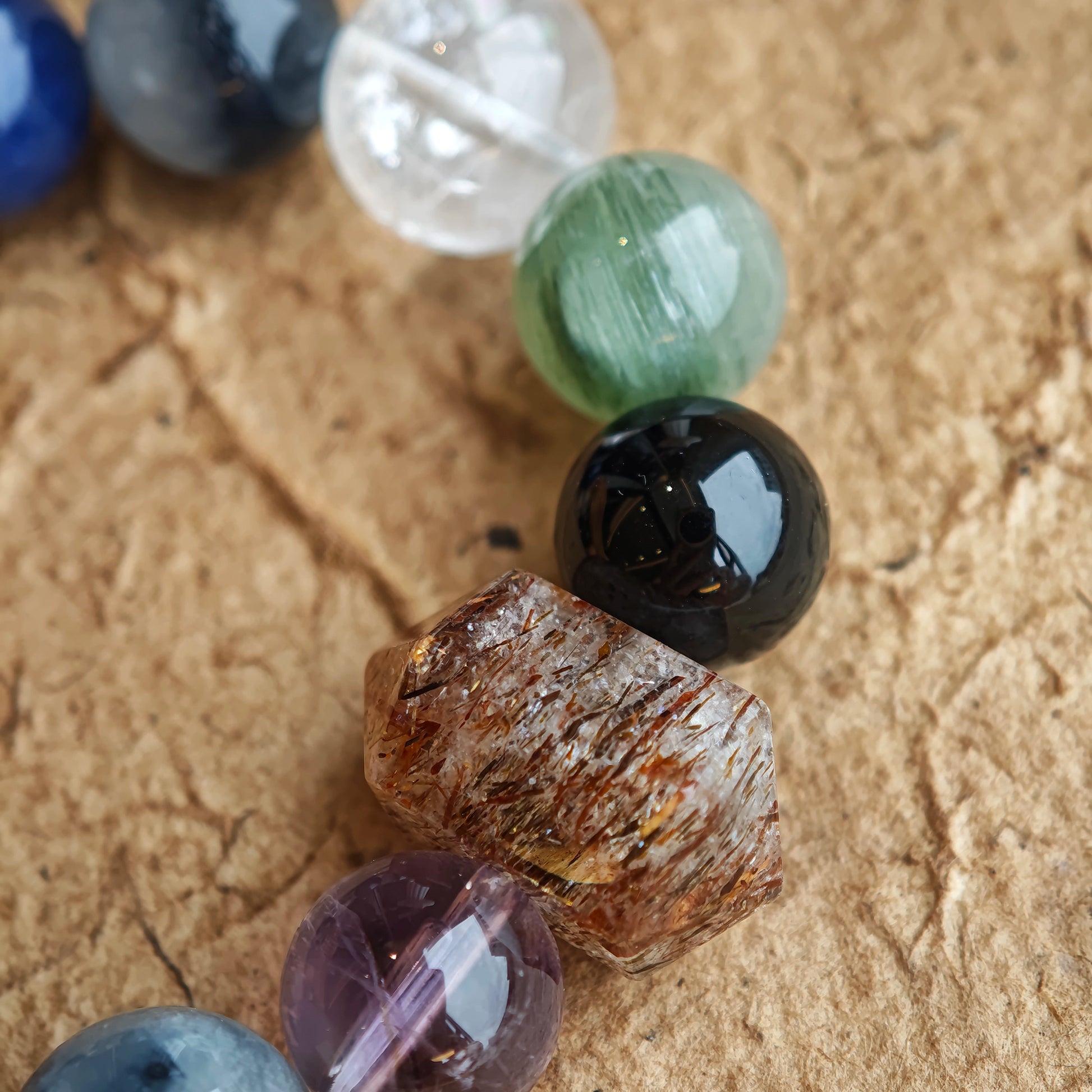 Enigmatic blue-grey energy radiates from Black Gold Super Seven, Herkimer diamonds, clear quartz, sandalwood, amethyst, silver obsidian, white phantom quartz, and kyanite.