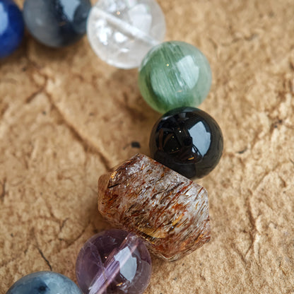 Enigmatic blue-grey energy radiates from Black Gold Super Seven, Herkimer diamonds, clear quartz, sandalwood, amethyst, silver obsidian, white phantom quartz, and kyanite.