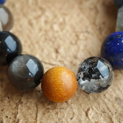 A shadowed aurora of crystals: Black Gold Super Seven, Herkimer diamonds, clear quartz, sandalwood, amethyst, silver obsidian, white phantom, and kyanite.