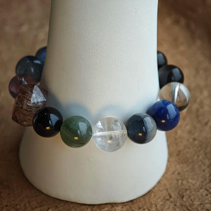 A twilight spectrum circles the wrist: Black Gold Super Seven, Herkimer diamonds, clear quartz, sandalwood, amethyst, silver obsidian, white phantom, and kyanite.