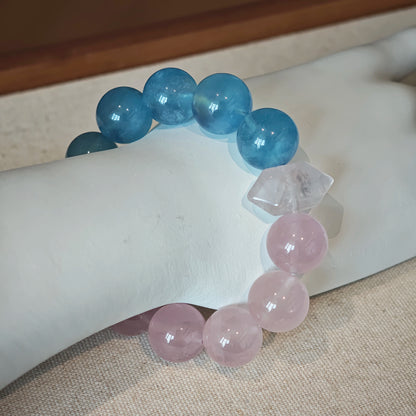 This bracelet consists of rose quartz and aquamarine. The bracelet features a bead pendant and a rhombic spacer, both of which are made of rose quartz. The bracelet is a combination of pink and blue colors.