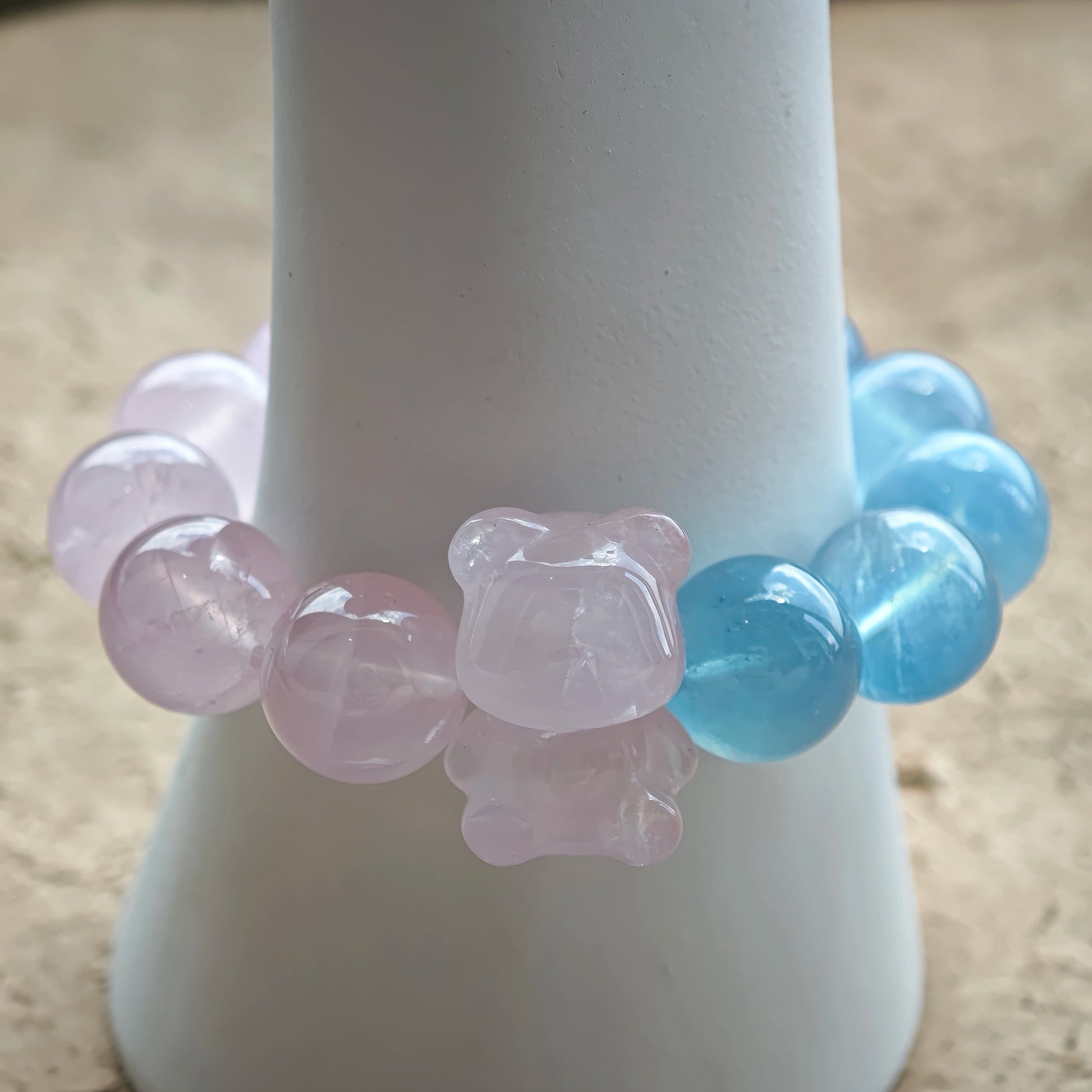 This bracelet consists of rose quartz and aquamarine. The bracelet features a bead pendant and a rhombic spacer, both of which are made of rose quartz. The bracelet is a combination of pink and blue colors.