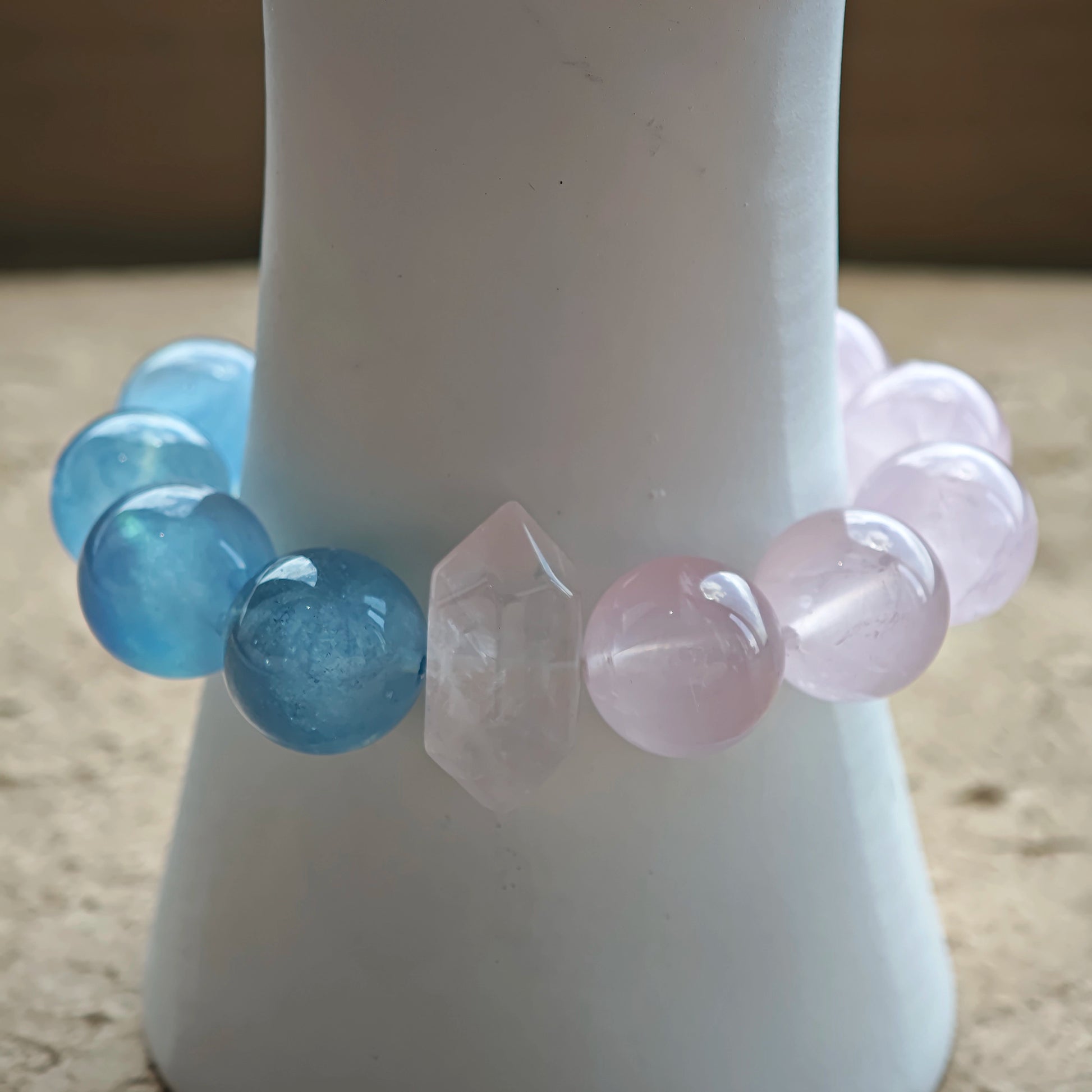This bracelet consists of rose quartz and aquamarine. The bracelet features a bead pendant and a rhombic spacer, both of which are made of rose quartz. The bracelet is a combination of pink and blue colors.