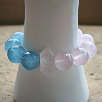 This bracelet consists of rose quartz and aquamarine. The bracelet features a bead pendant and a rhombic spacer, both of which are made of rose quartz. The bracelet is a combination of pink and blue colors.