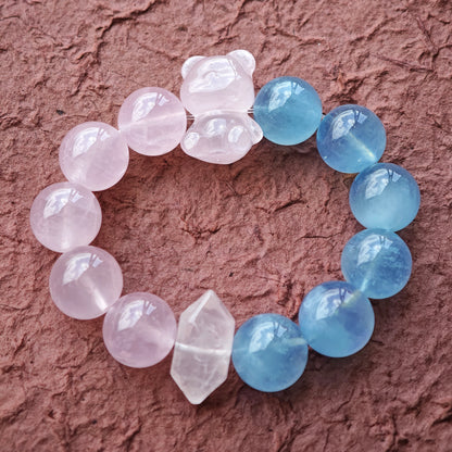 This bracelet consists of rose quartz and aquamarine. The bracelet features a bead pendant and a rhombic spacer, both of which are made of rose quartz. The bracelet is a combination of pink and blue colors.