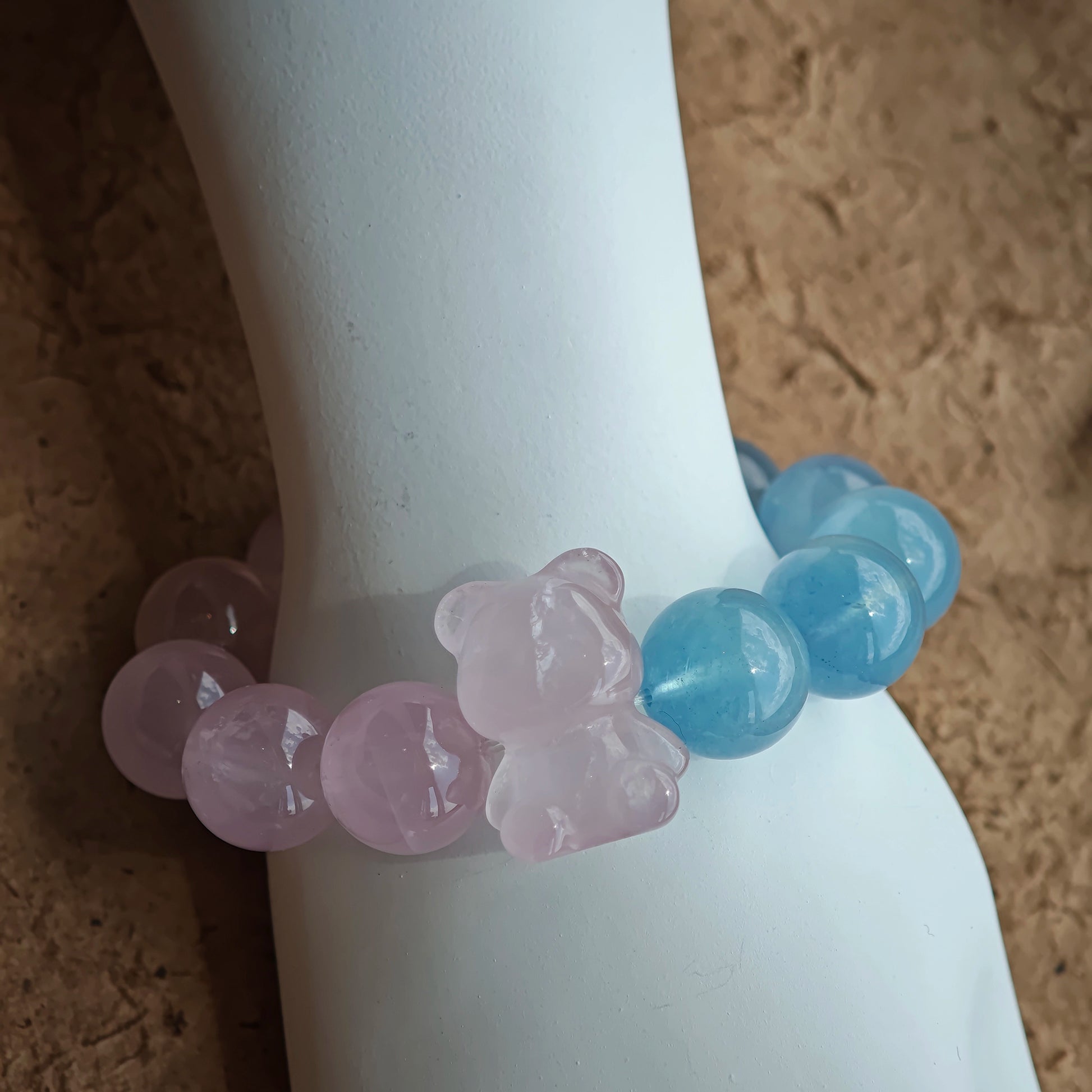 This bracelet consists of rose quartz and aquamarine. The bracelet features a bead pendant and a rhombic spacer, both of which are made of rose quartz. The bracelet is a combination of pink and blue colors.