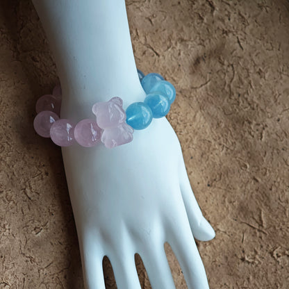 This bracelet consists of rose quartz and aquamarine. The bracelet features a bead pendant and a rhombic spacer, both of which are made of rose quartz. The bracelet is a combination of pink and blue colors.