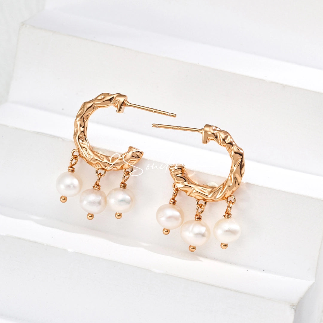 This is a pair of earrings made of sterling silver and natural pearls. The sterling silver is plated with gold, and a crescent-shaped pendant holds three pearls, each approximately 6mm in diameter. The earrings are approximately 2cm in height, a perfect size.