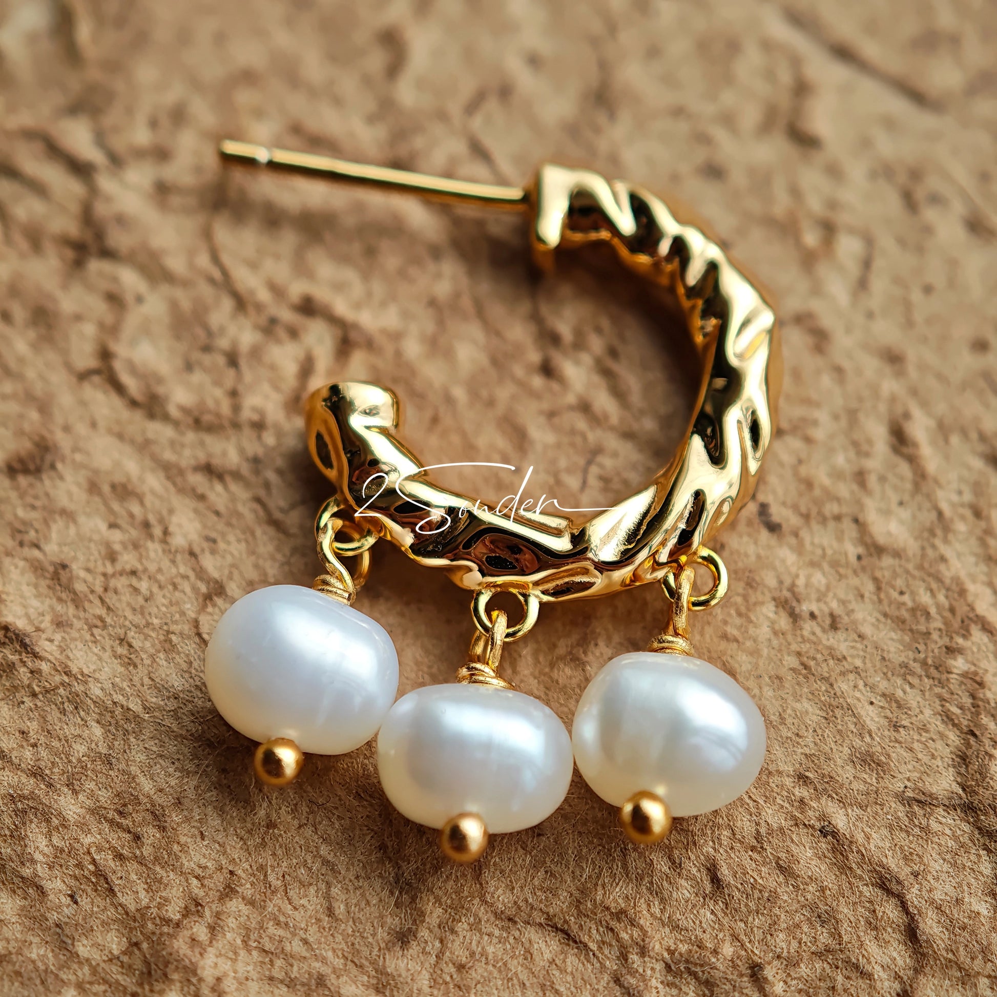 This is a pair of earrings made of sterling silver and natural pearls. The sterling silver is plated with gold, and a crescent-shaped pendant holds three pearls, each approximately 6mm in diameter. The earrings are approximately 2cm in height, a perfect size.