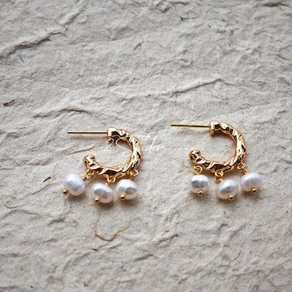 This is a pair of earrings made of sterling silver and natural pearls. The sterling silver is plated with gold, and a crescent-shaped pendant holds three pearls, each approximately 6mm in diameter. The earrings are approximately 2cm in height, a perfect size.