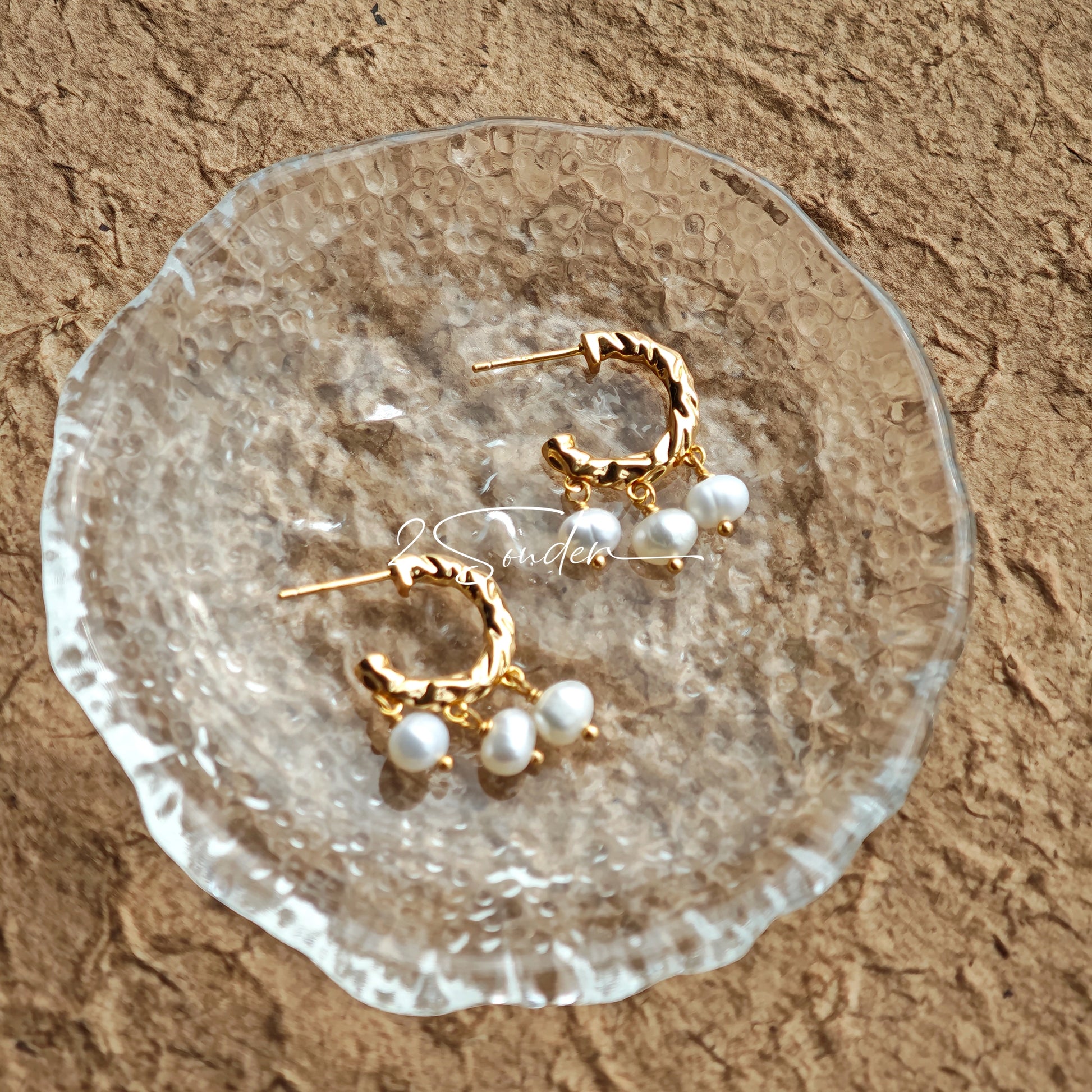 This is a pair of earrings made of sterling silver and natural pearls. The sterling silver is plated with gold, and a crescent-shaped pendant holds three pearls, each approximately 6mm in diameter. The earrings are approximately 2cm in height, a perfect size.