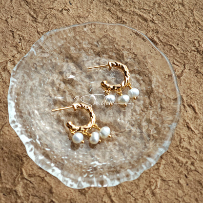 This is a pair of earrings made of sterling silver and natural pearls. The sterling silver is plated with gold, and a crescent-shaped pendant holds three pearls, each approximately 6mm in diameter. The earrings are approximately 2cm in height, a perfect size.