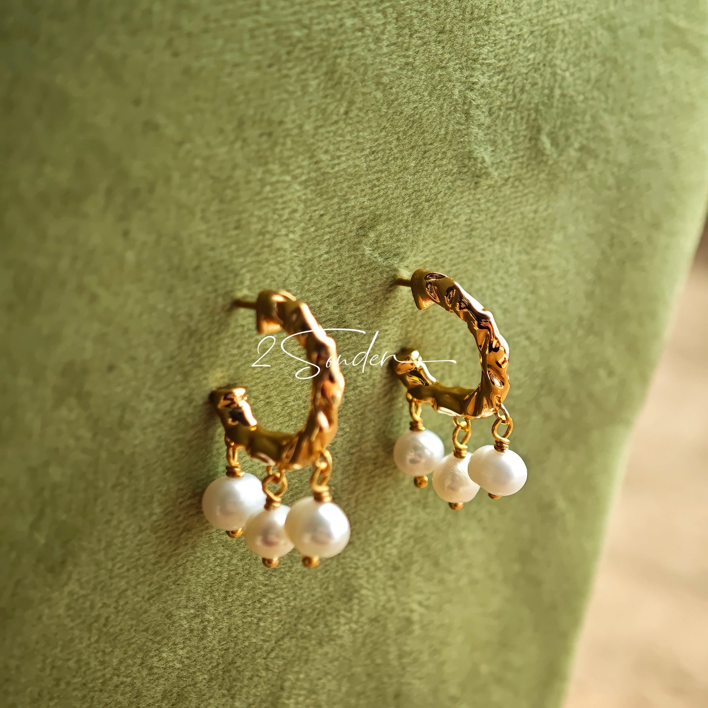 This is a pair of earrings made of sterling silver and natural pearls. The sterling silver is plated with gold, and a crescent-shaped pendant holds three pearls, each approximately 6mm in diameter. The earrings are approximately 2cm in height, a perfect size.