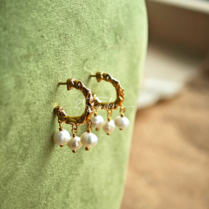 This is a pair of earrings made of sterling silver and natural pearls. The sterling silver is plated with gold, and a crescent-shaped pendant holds three pearls, each approximately 6mm in diameter. The earrings are approximately 2cm in height, a perfect size.