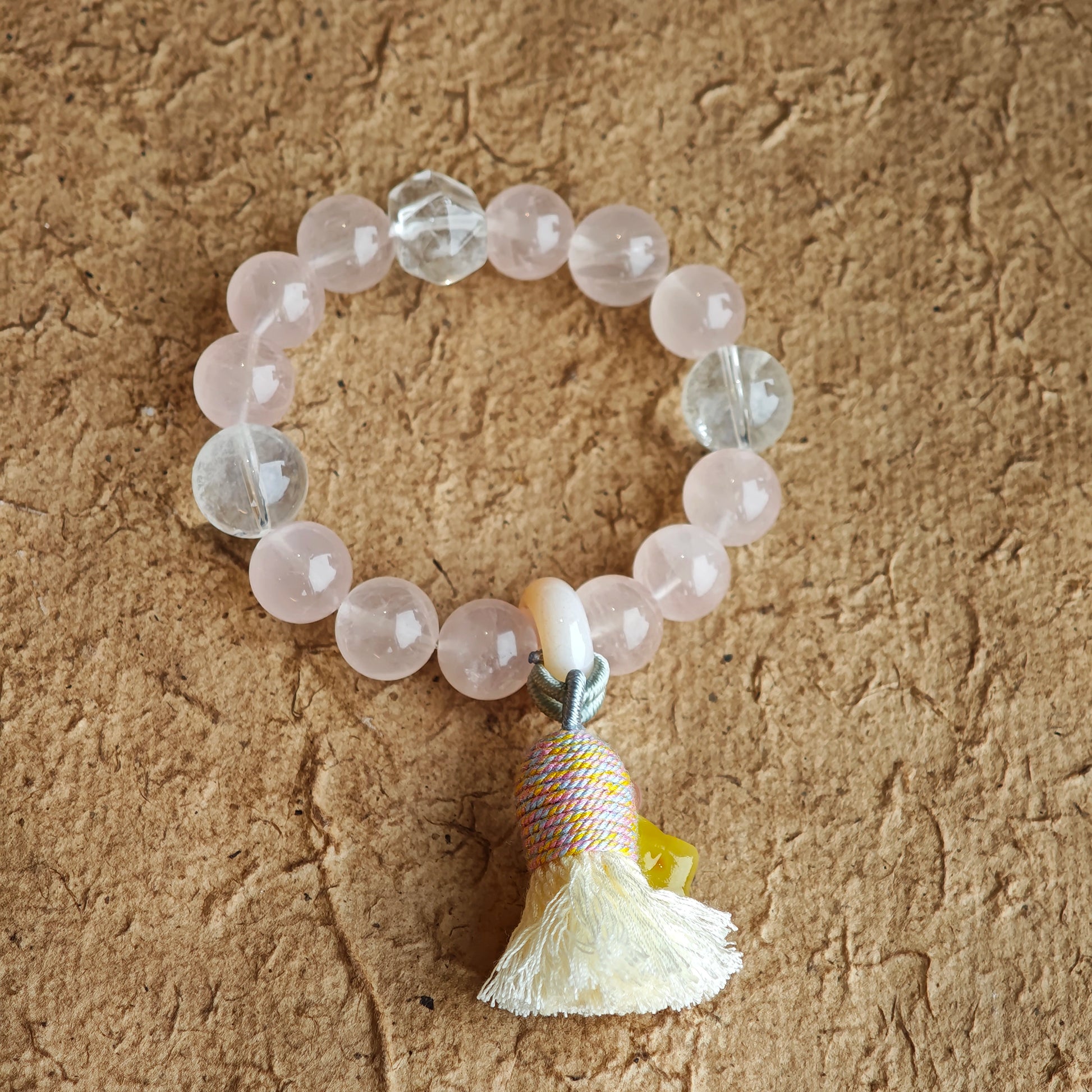 Soft rose quartz and rare blue-needle crystals entwine, while an amber star, sliding agate bead, and silky tassel give the boho design its final flourish.