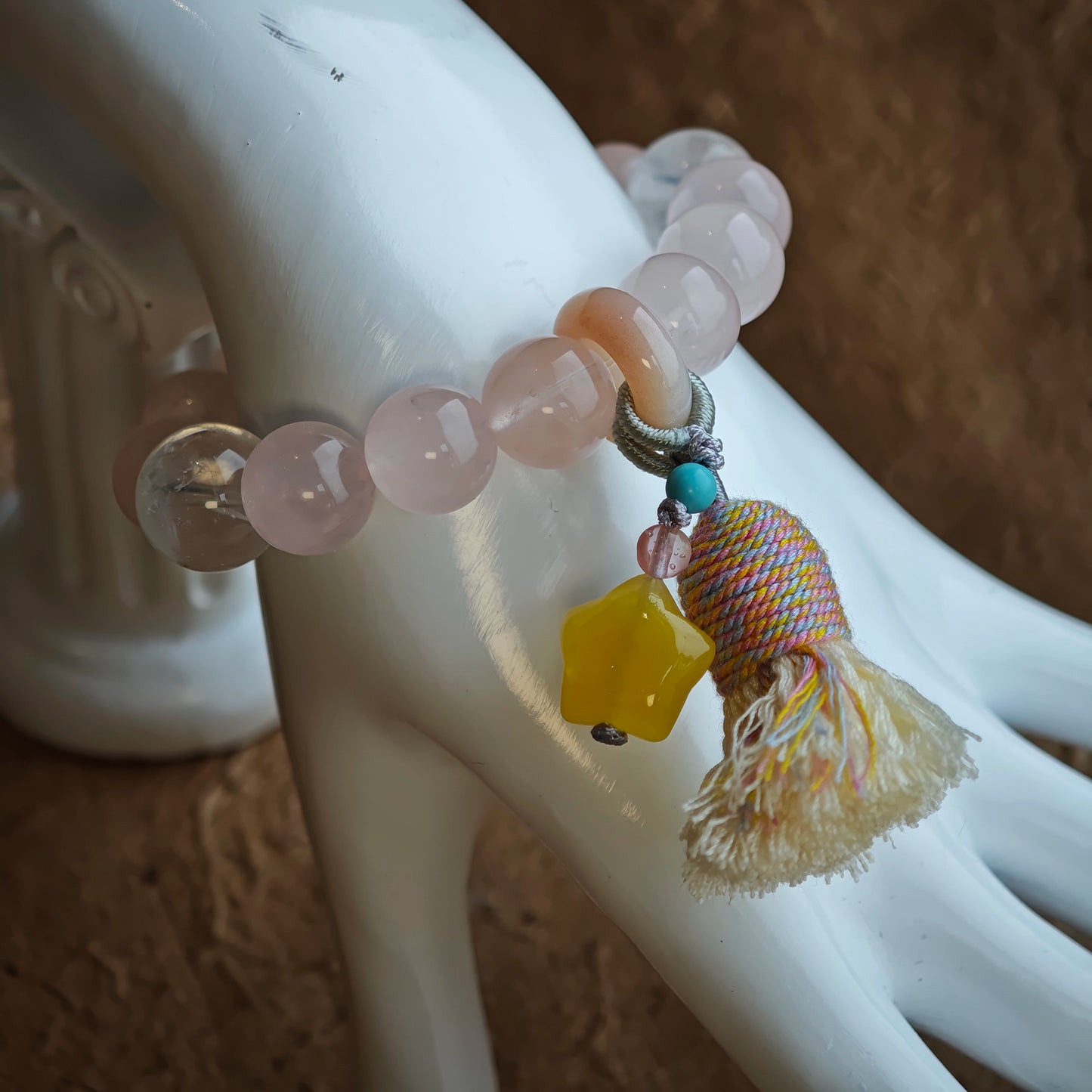 Soft-hued stones embrace icy threads, crowned by an amber star, sliding agate, and delicate tassel for carefree style.