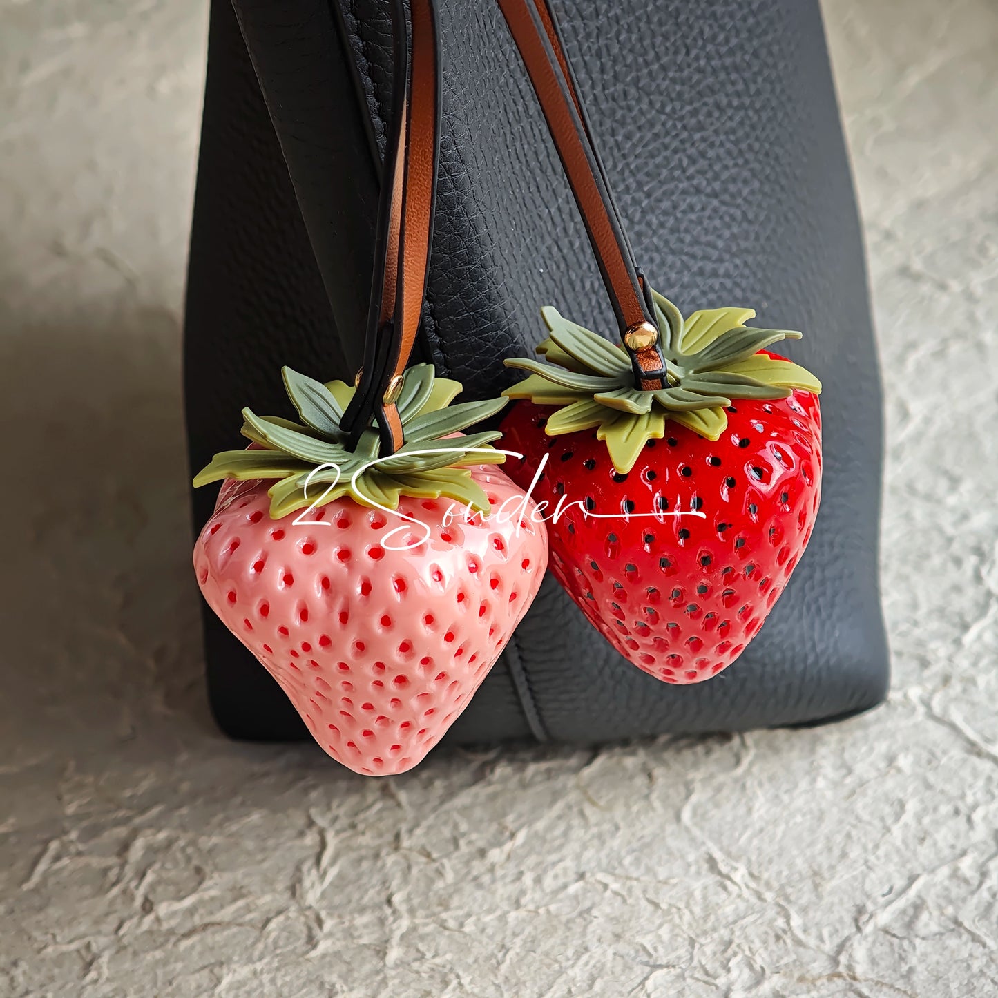 This is a simulated strawberry bag charm. The charm features a strawberry, the same size as a real strawberry, and is made of high-quality resin, giving it a very realistic appearance. It also has a leather cord attached, allowing it to be hung on bags, earphone cases, or used as a keychain. It's versatile and very cute.