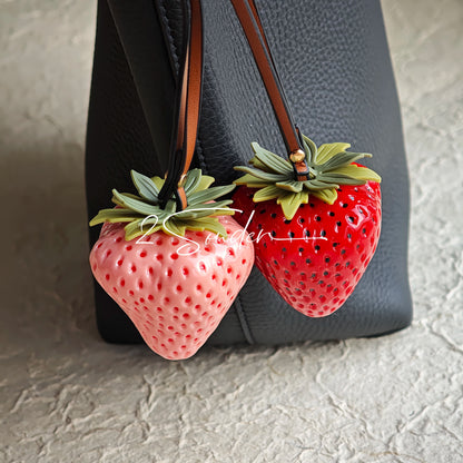 This is a simulated strawberry bag charm. The charm features a strawberry, the same size as a real strawberry, and is made of high-quality resin, giving it a very realistic appearance. It also has a leather cord attached, allowing it to be hung on bags, earphone cases, or used as a keychain. It's versatile and very cute.