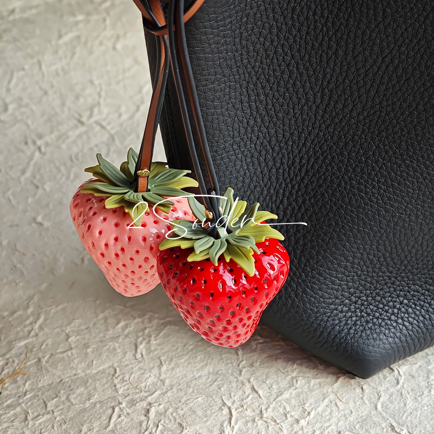 This is a simulated strawberry bag charm. The charm features a strawberry, the same size as a real strawberry, and is made of high-quality resin, giving it a very realistic appearance. It also has a leather cord attached, allowing it to be hung on bags, earphone cases, or used as a keychain. It's versatile and very cute.