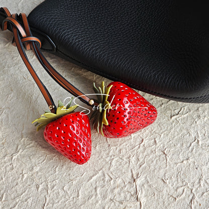 This is a simulated strawberry bag charm. The charm features a strawberry, the same size as a real strawberry, and is made of high-quality resin, giving it a very realistic appearance. It also has a leather cord attached, allowing it to be hung on bags, earphone cases, or used as a keychain. It's versatile and very cute.
