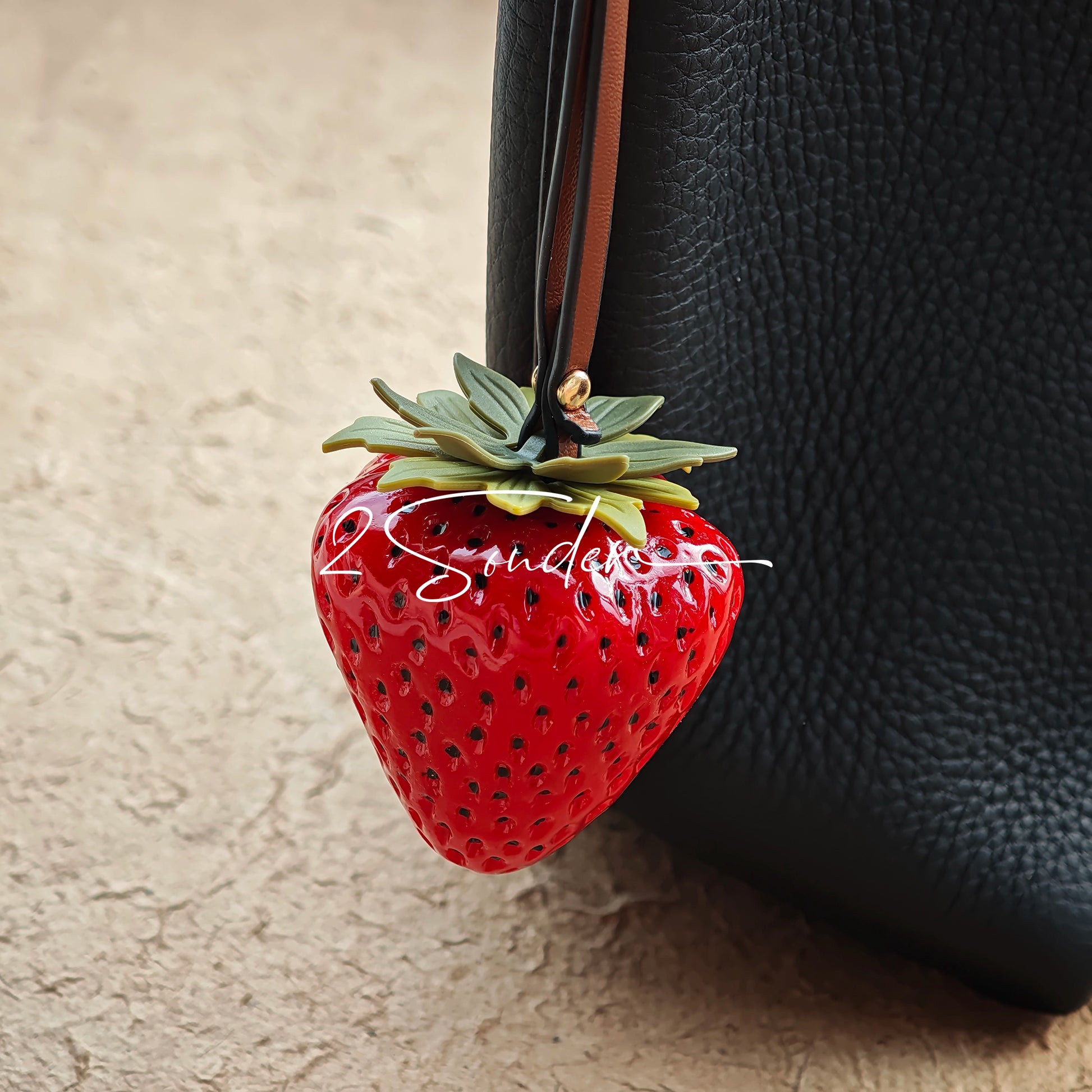 This is a simulated strawberry bag charm. The charm features a strawberry, the same size as a real strawberry, and is made of high-quality resin, giving it a very realistic appearance. It also has a leather cord attached, allowing it to be hung on bags, earphone cases, or used as a keychain. It's versatile and very cute.