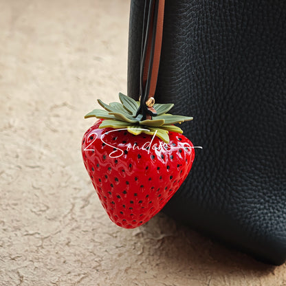 This is a simulated strawberry bag charm. The charm features a strawberry, the same size as a real strawberry, and is made of high-quality resin, giving it a very realistic appearance. It also has a leather cord attached, allowing it to be hung on bags, earphone cases, or used as a keychain. It's versatile and very cute.
