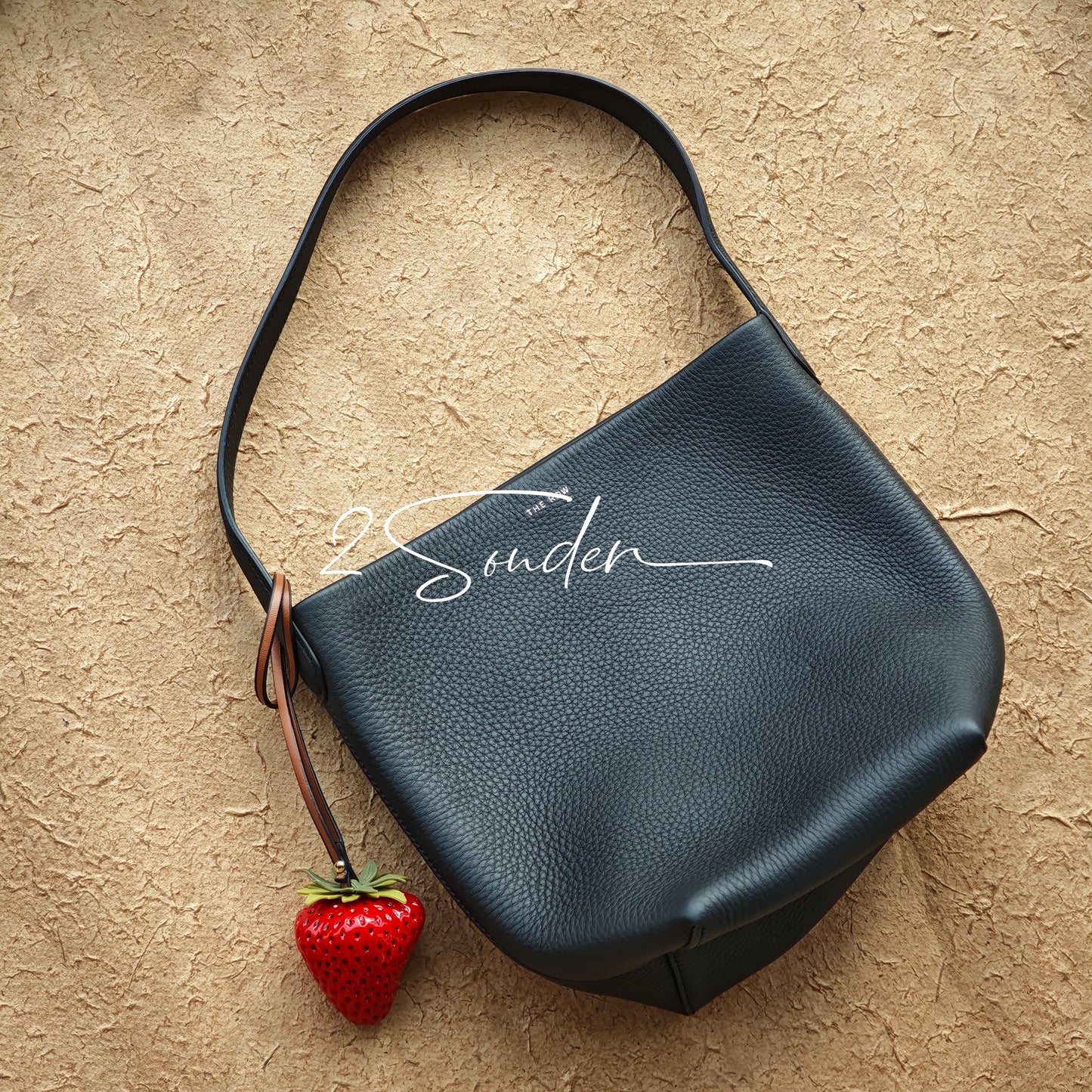 This is a simulated strawberry bag charm. The charm features a strawberry, the same size as a real strawberry, and is made of high-quality resin, giving it a very realistic appearance. It also has a leather cord attached, allowing it to be hung on bags, earphone cases, or used as a keychain. It's versatile and very cute.