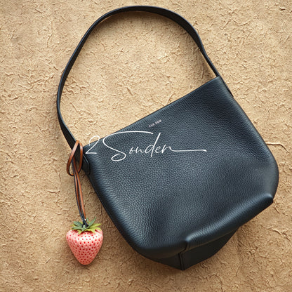 This is a simulated strawberry bag charm. The charm features a strawberry, the same size as a real strawberry, and is made of high-quality resin, giving it a very realistic appearance. It also has a leather cord attached, allowing it to be hung on bags, earphone cases, or used as a keychain. It's versatile and very cute.