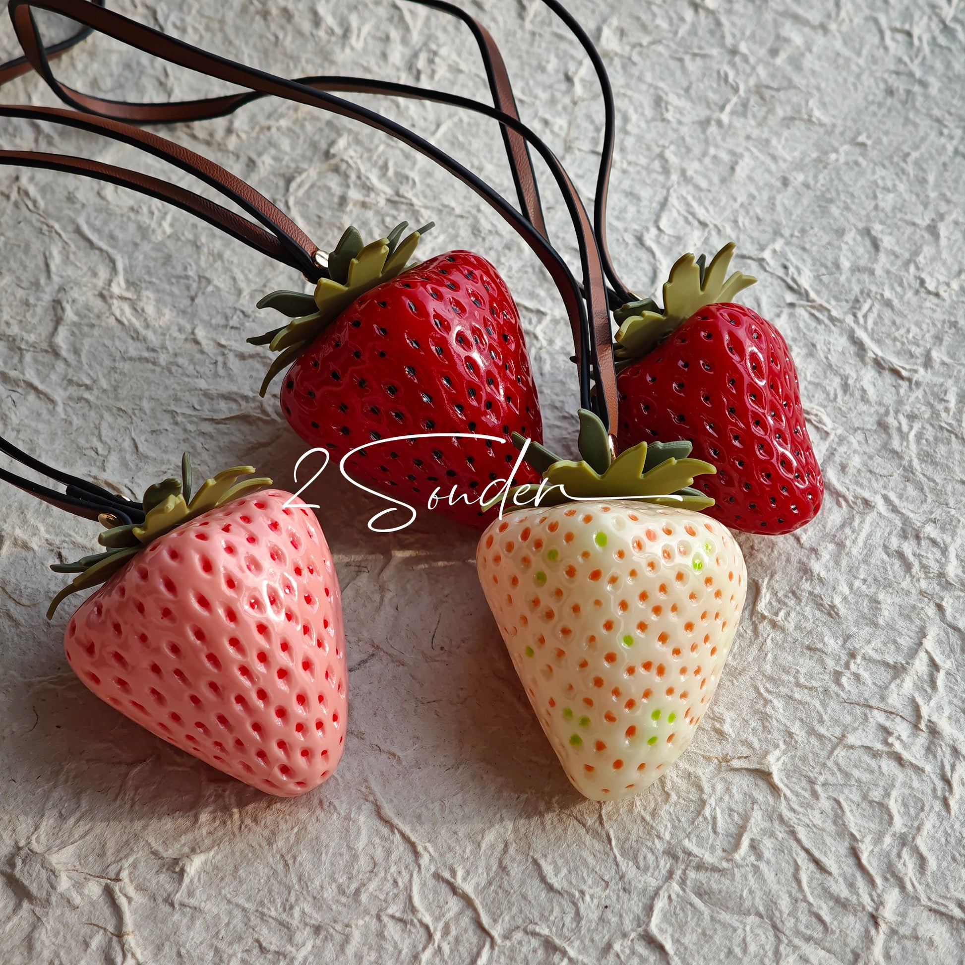 This is a simulated strawberry bag charm. The charm features a strawberry, the same size as a real strawberry, and is made of high-quality resin, giving it a very realistic appearance. It also has a leather cord attached, allowing it to be hung on bags, earphone cases, or used as a keychain. It's versatile and very cute.