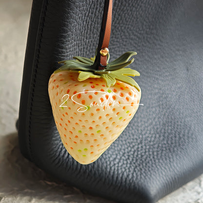 This is a simulated strawberry bag charm. The charm features a strawberry, the same size as a real strawberry, and is made of high-quality resin, giving it a very realistic appearance. It also has a leather cord attached, allowing it to be hung on bags, earphone cases, or used as a keychain. It's versatile and very cute.