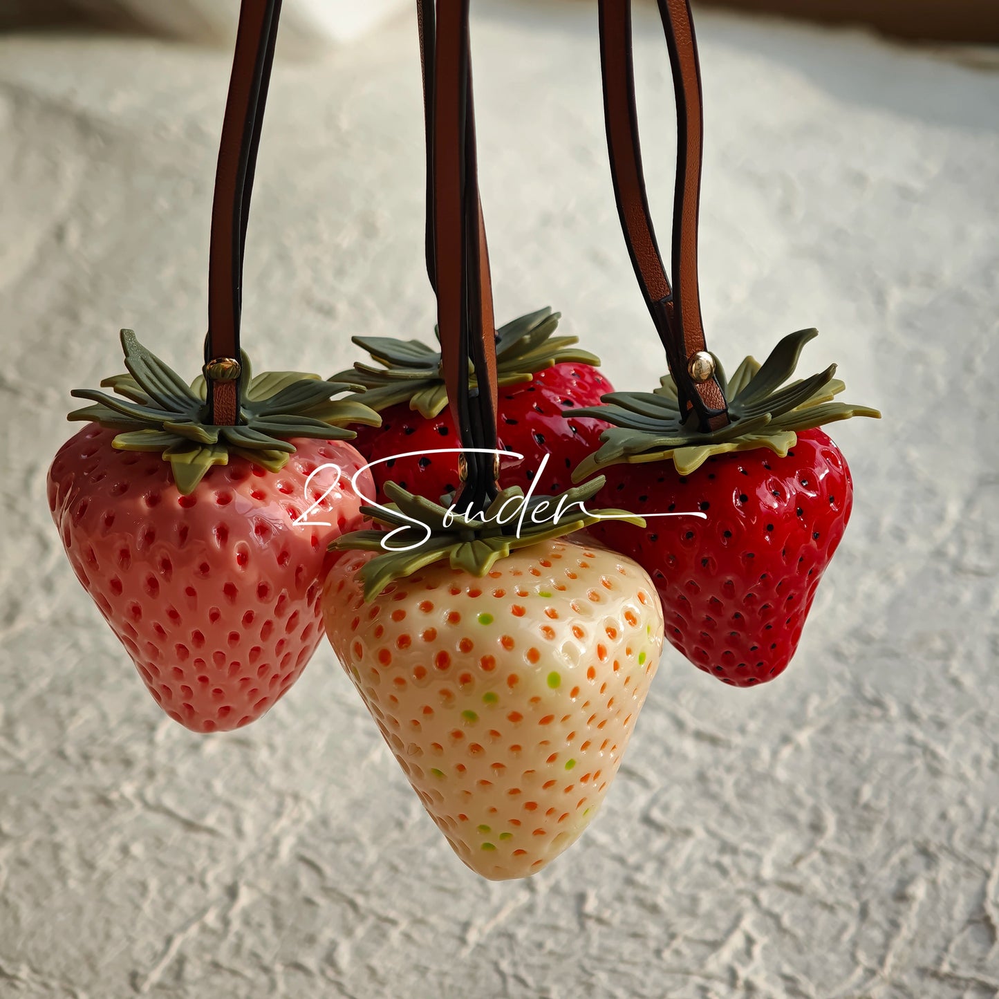 This is a simulated strawberry bag charm. The charm features a strawberry, the same size as a real strawberry, and is made of high-quality resin, giving it a very realistic appearance. It also has a leather cord attached, allowing it to be hung on bags, earphone cases, or used as a keychain. It's versatile and very cute.