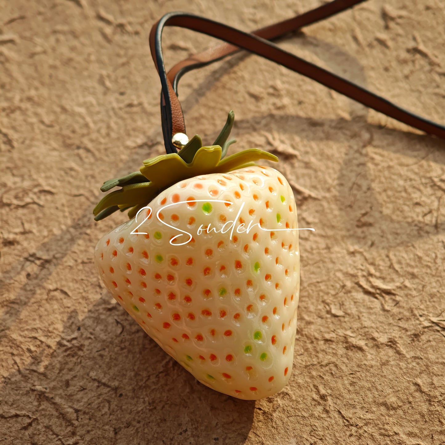 This is a simulated strawberry bag charm. The charm features a strawberry, the same size as a real strawberry, and is made of high-quality resin, giving it a very realistic appearance. It also has a leather cord attached, allowing it to be hung on bags, earphone cases, or used as a keychain. It's versatile and very cute.