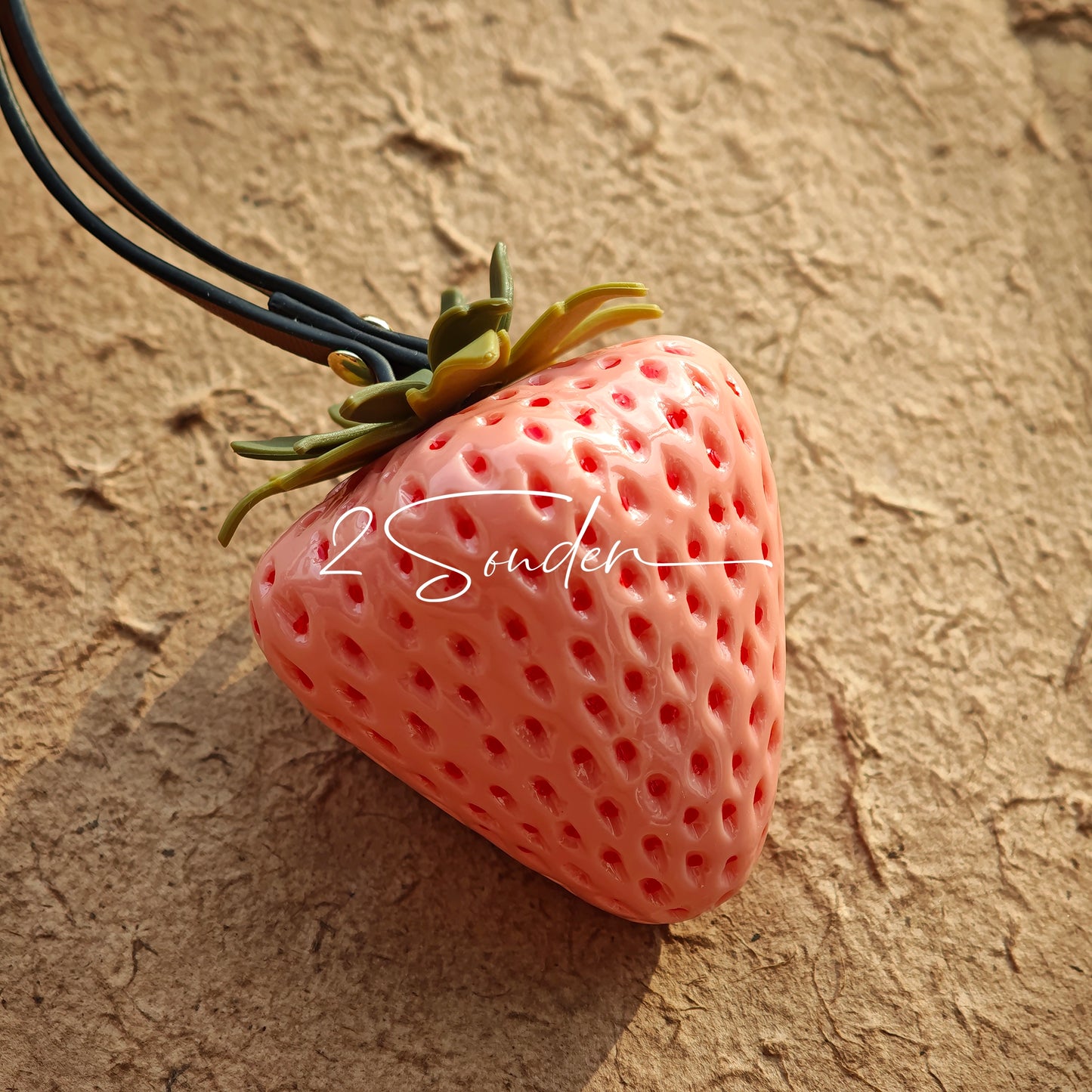 This is a simulated strawberry bag charm. The charm features a strawberry, the same size as a real strawberry, and is made of high-quality resin, giving it a very realistic appearance. It also has a leather cord attached, allowing it to be hung on bags, earphone cases, or used as a keychain. It's versatile and very cute.