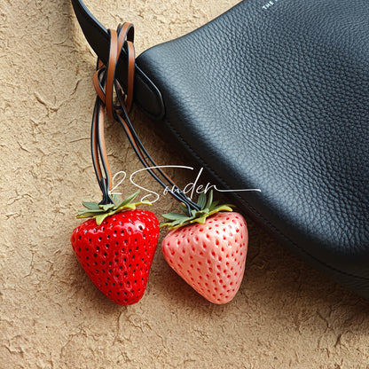 This is a simulated strawberry bag charm. The charm features a strawberry, the same size as a real strawberry, and is made of high-quality resin, giving it a very realistic appearance. It also has a leather cord attached, allowing it to be hung on bags, earphone cases, or used as a keychain. It's versatile and very cute.