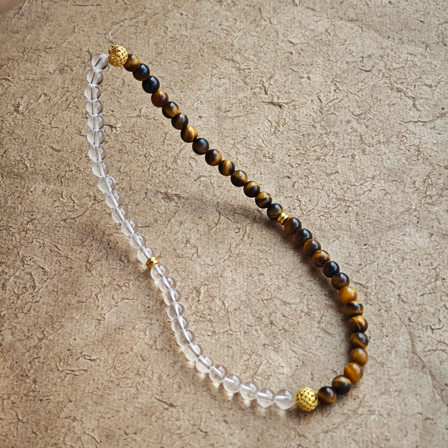 This is a necklace with tiger's eye, clear quartz, gold-plated spacer and elastic cord.