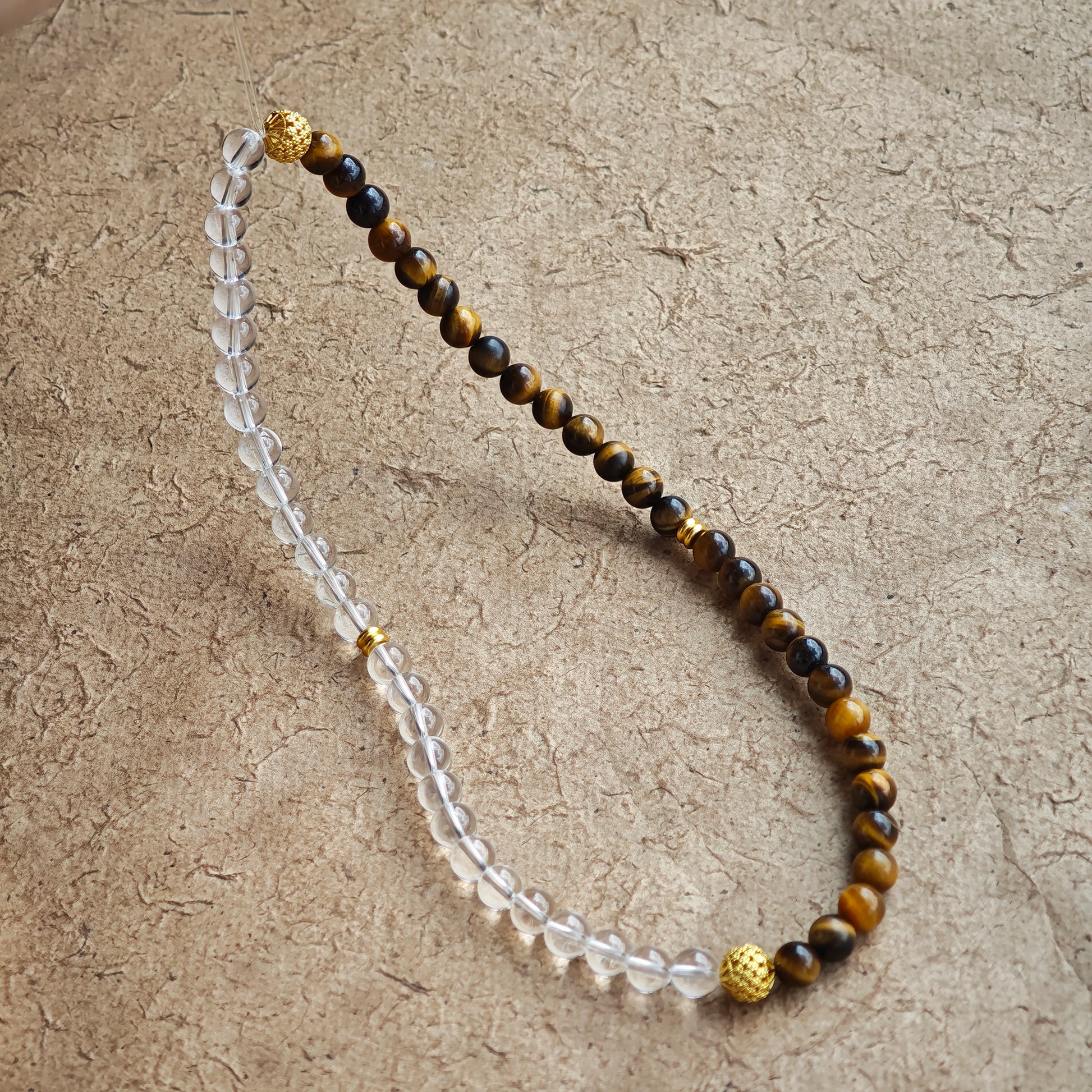 This is a necklace with tiger's eye, clear quartz, gold-plated spacer and elastic cord.