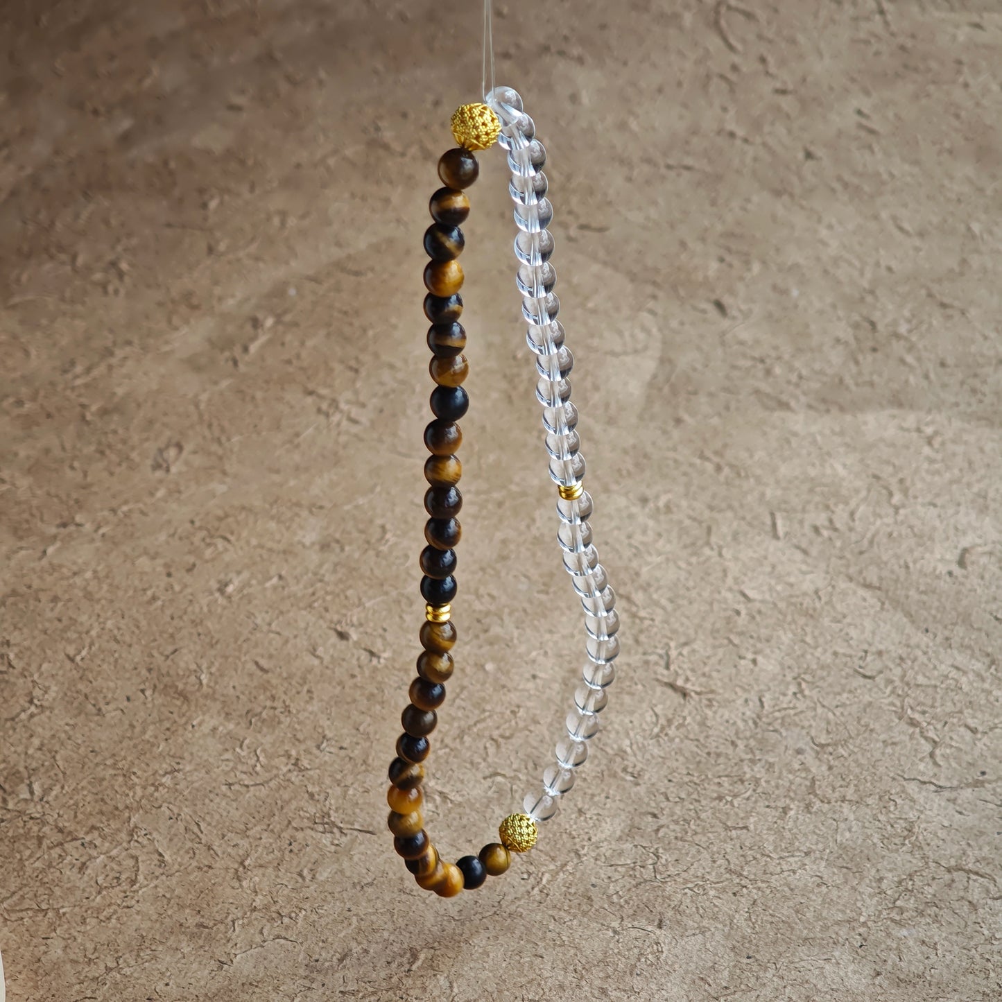 This is a necklace with tiger's eye, clear quartz, gold-plated spacer and elastic cord.