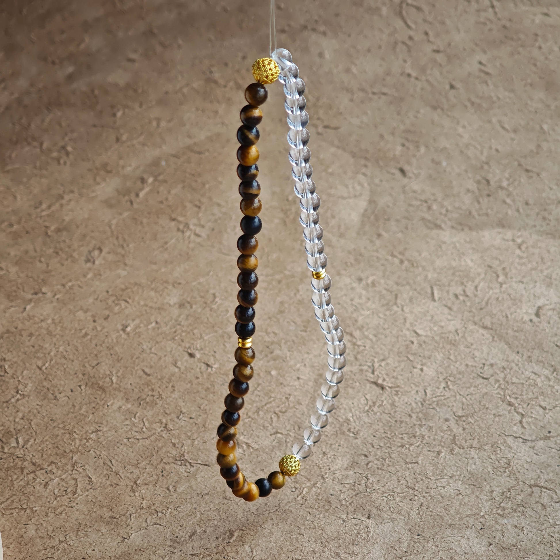 This is a necklace with tiger's eye, clear quartz, gold-plated spacer and elastic cord.