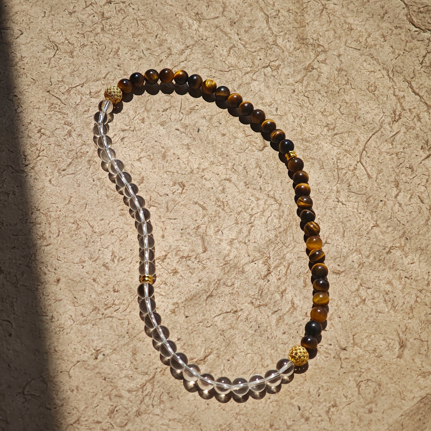 This is a necklace with tiger's eye, clear quartz, gold-plated spacer and elastic cord.