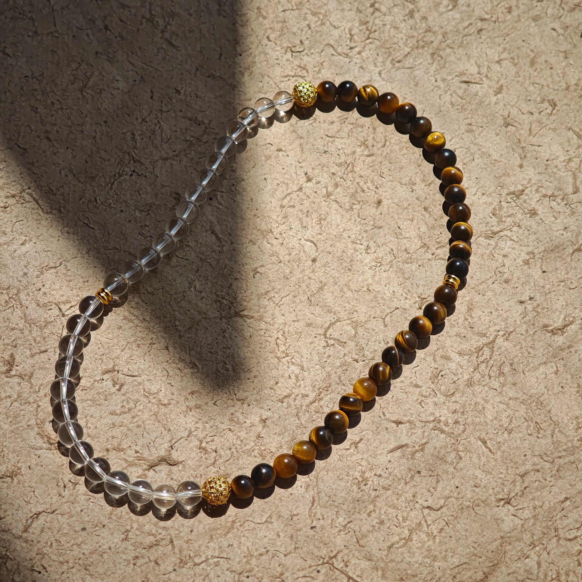 This is a necklace with tiger's eye, clear quartz, gold-plated spacer and elastic cord.