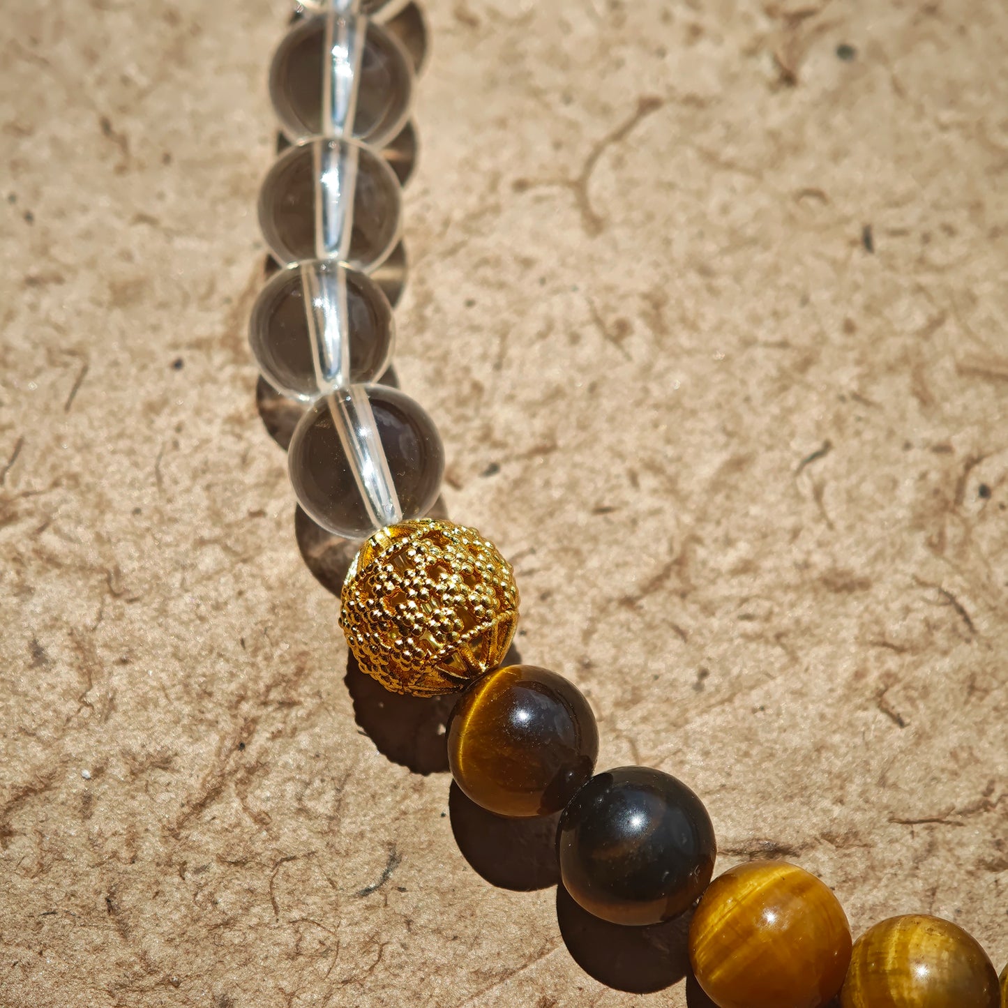 This is a necklace with tiger's eye, clear quartz, gold-plated spacer and elastic cord.
