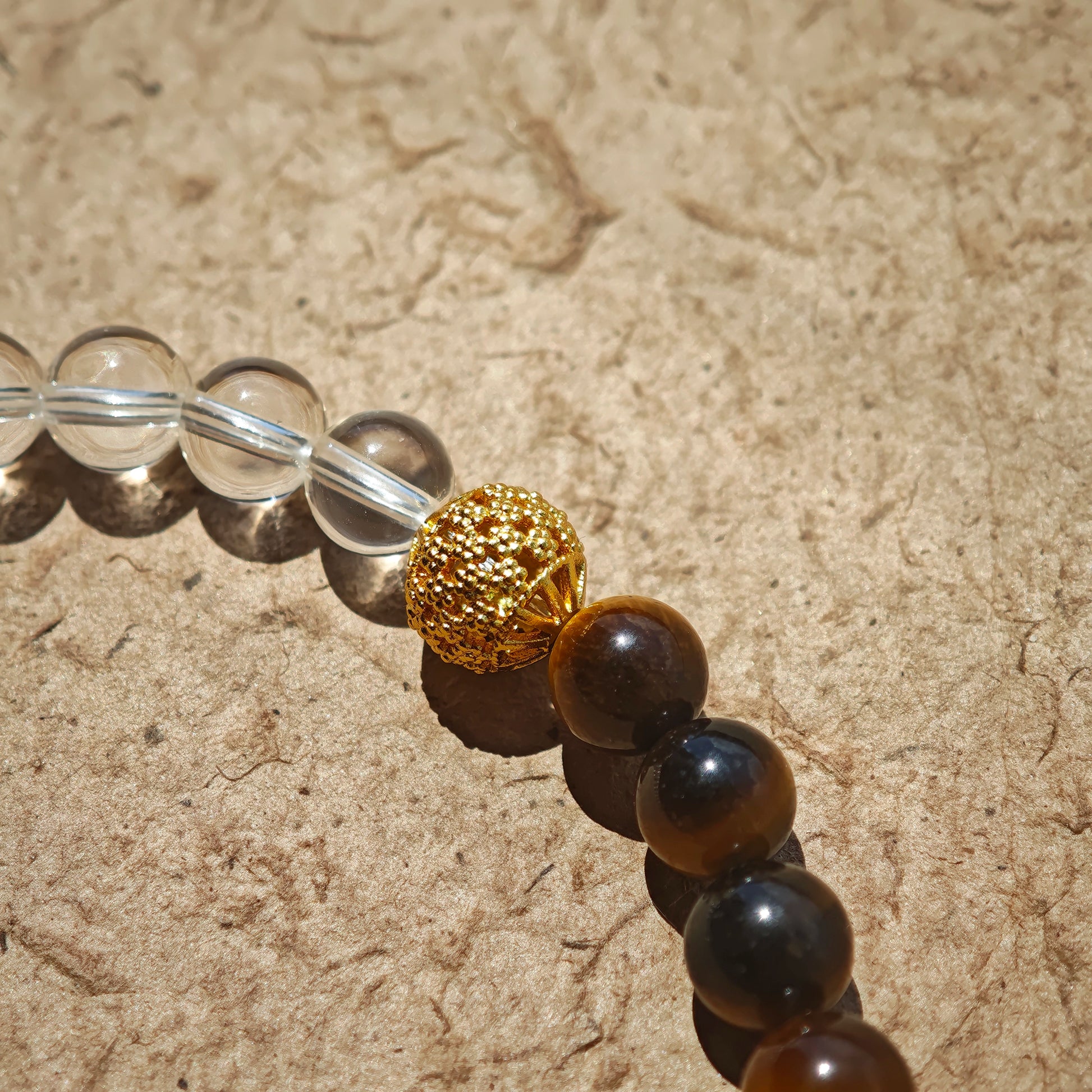 This is a necklace with tiger's eye, clear quartz, gold-plated spacer and elastic cord.
