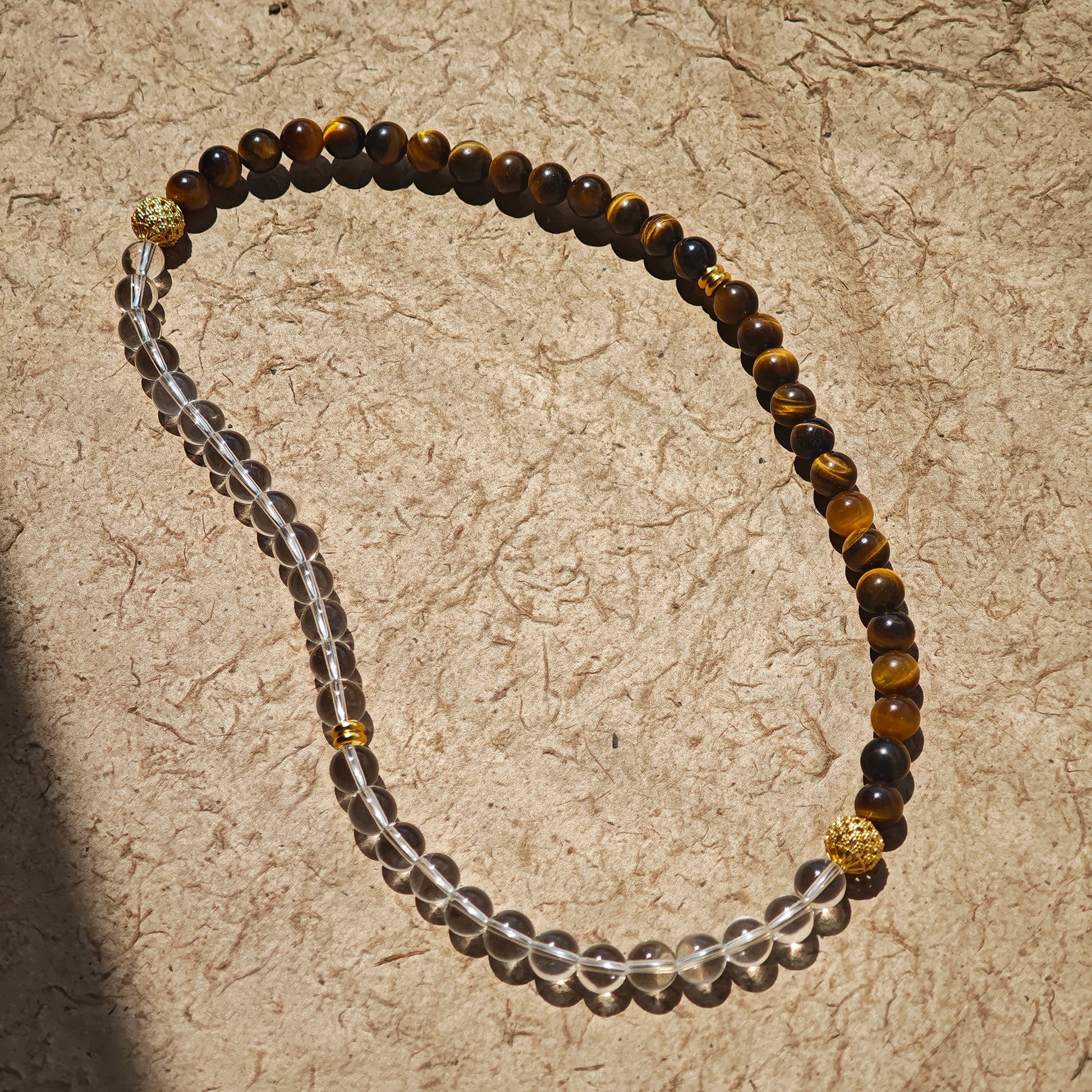 This is a necklace with tiger's eye, clear quartz, gold-plated spacer and elastic cord.