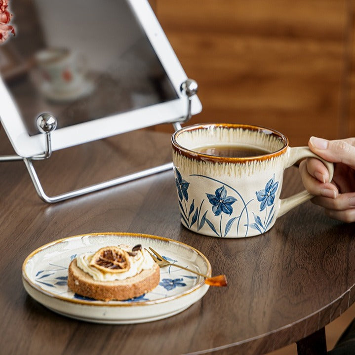 This is a vintage ceramic coffee cup and saucer set with retro floral patterns. The cup capacity is 385ml, and it comes with a saucer. This mid-century inspired ceramic coffee mug set features high-temperature decal floral patterns, kiln-change glaze effects, and elegant gold detailing.