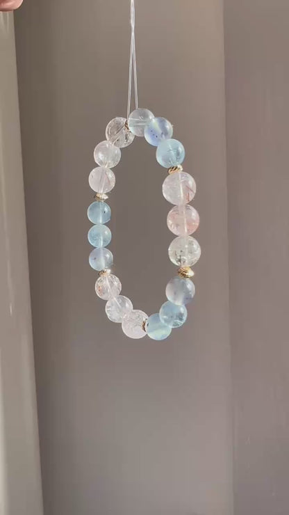 The piece unites aquamarine’s calm with rutile’s sparkle, ringed in subtle gold.