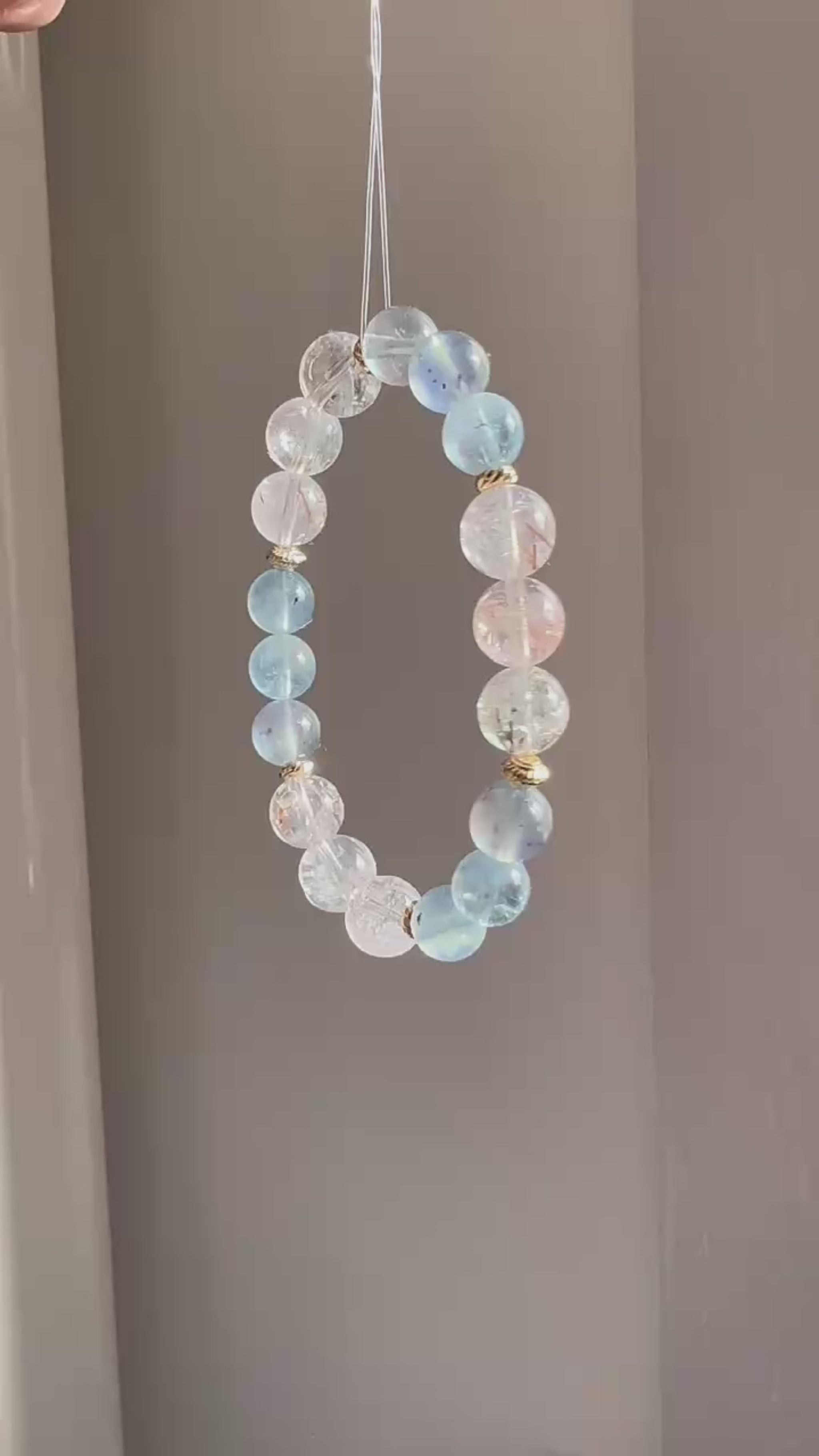 The piece unites aquamarine’s calm with rutile’s sparkle, ringed in subtle gold.