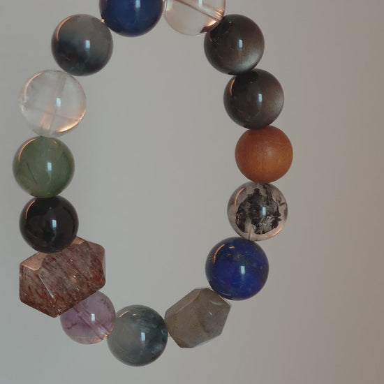 Cool lunar tones bloom from Black Gold Super Seven, Herkimer diamonds, clear quartz, sandalwood, amethyst, silver obsidian, white phantom quartz, and kyanite.