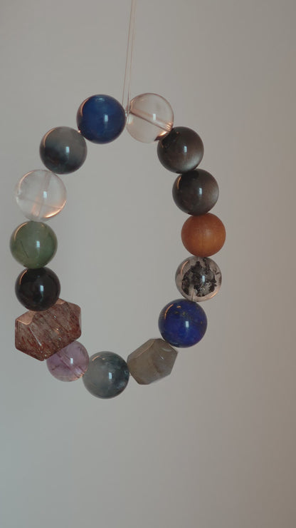 Cool lunar tones bloom from Black Gold Super Seven, Herkimer diamonds, clear quartz, sandalwood, amethyst, silver obsidian, white phantom quartz, and kyanite.